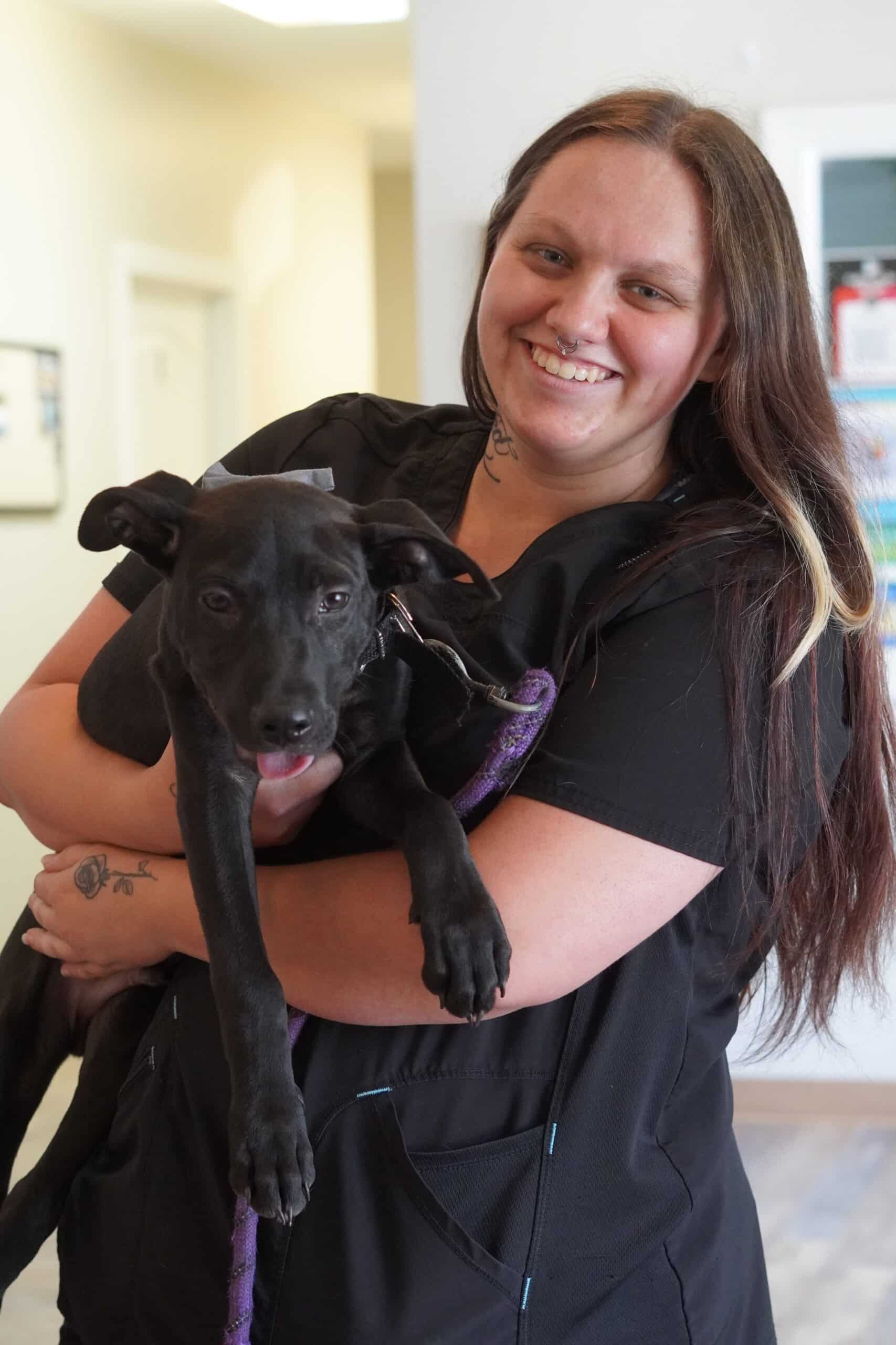 DSC02599 A woman smiles while holding a black dog in her arms